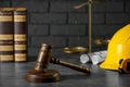 Construction and land law concepts. Judge gavel, books, protective helmet, scales of justice with drawings on grey table Royalty Free Stock Photo