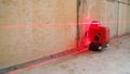 The construction laser level is on the floor. The beam is directed at the wall. Aligning the walls with a laser level Royalty Free Stock Photo