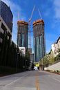 Construction lots of high-rise glass buildings with large yellow construction cranes against the blue sky. Royalty Free Stock Photo