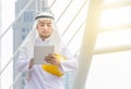 Construction and maintenance concept, Arab Middle Eastern architect holding yellow helmet and checking tablet PC with city backgro Royalty Free Stock Photo