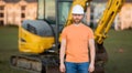 Construction man with excavator at industrial site. Worker in helmet build with bulldozer. Engineer work with builder contractor Royalty Free Stock Photo