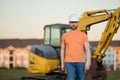 Construction man with excavator at industrial site. Worker in helmet build with bulldozer. Engineer work with builder Royalty Free Stock Photo