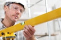 Construction man worker measure with level laser wear hard hat and protective glasses at interior building site