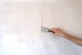 Construction man worker repairing a crack wall of a home, plastering cement on wall. Builder applying white cement to a Royalty Free Stock Photo