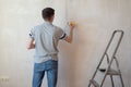 Construction man worker repairing a crack wall of a home, plastering cement on wall. Builder applying white cement to a Royalty Free Stock Photo