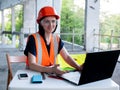 Construction management. Woman manager at a construction site. Woman in a robot builder vest with a laptop. Girl on the Royalty Free Stock Photo