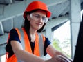 Construction management. Woman manager at a construction site. Woman in a robot builder vest with a laptop. Girl on the Royalty Free Stock Photo