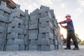 A construction manager inspects a high stack of fresh concrete cinder blocks, focusing on inventory and quality control at a small Royalty Free Stock Photo