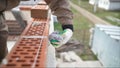 Worker wipes the seams outside the brick house. The builder processes the brickwork. Construction mason worker bricklayer