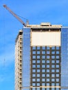 Construction of a modern concrete building with a glass facade, a reflection of the blue sky and tower cranes Royalty Free Stock Photo