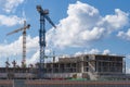 Construction of multi-storey building. High altitude cranes. Background - blue sky with clouds