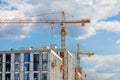 Construction of a multi-storey high-rise residential building using tower cranes against a blue slightly cloudy sky Royalty Free Stock Photo