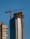 A crane is seen at the top of a high rise building under construction