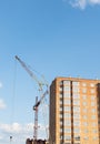 Construction of a new apartment building, against the blue sky, a high-rise construction crane. Vertical photo Royalty Free Stock Photo