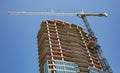 A crane rissing above a new high rise building under construction. Royalty Free Stock Photo