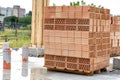 Construction of new house concept. Vertical photo red rectangular brick tray lay in stack on floor foundation outside Royalty Free Stock Photo