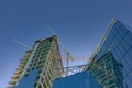 Construction of new modern building. Glass walls of a high-rise office building and construction cranes. Low view Royalty Free Stock Photo