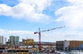 Construction of a new multi-storey building in the city, red construction crane on a blue cloudy sky background, construction site Royalty Free Stock Photo