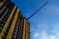 Construction of a new multi-storey building. tall orange crane builds floors. carrying heavy and gray concrete blocks. windows not Royalty Free Stock Photo