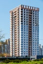 Construction of a new multi-storey residential building with a square-shaped building against a background of blue sky and green Royalty Free Stock Photo