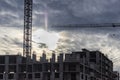 Construction of a panel frame house at sunset using a tower crane. Back light. Work at night on the construction of a residential Royalty Free Stock Photo