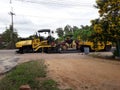 The construction of paved road by workers with yellow heavy tractor vibratory roller and Asphalt Paver Machine