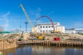 Construction of pedestrian bridge over river with special heavy machinery and equipment on sunny day. Working process of building Royalty Free Stock Photo