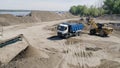 The construction process. Scene. Trucks carry materials for construction in an empty area behind which there is a river Royalty Free Stock Photo