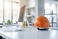 Construction professional workspace: Computer, keyboard and helmet on desk Royalty Free Stock Photo