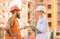 Construction project inspecting. Safety inspector concept. Woman inspector and bearded brutal builder discuss Royalty Free Stock Photo