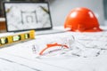 Construction protective glasses,orange hard hat, laptop  with drawings, level meter lying in a  blueprints on a table Royalty Free Stock Photo