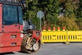 Construction road roller on the roadway. Yellow safety barriers with red signal.