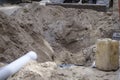 Construction of a road. A shovel pushes sand to a hole in the road, in the foreground out of focus a sewage pipe and a jerry can Royalty Free Stock Photo