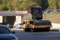 A construction roller rolls asphalt on a city highway. Special equipment is bypassed by cars. Royalty Free Stock Photo