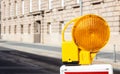 Construction safety. Street barricade with warning signal lamp on a road, blur building background