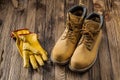 Construction safety tools yellow working gloves and leather working boots on vintage wooden background Royalty Free Stock Photo