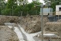 A construction shaft on a construction site with a metal ladder and with a metal fence making out the border of the site.