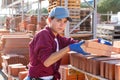 Construction shop worker stacks bricks on an open-air site