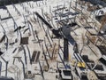 Construction site aerial view. Mall building base with solid concrete pillars. Heavy machinery and high tower crane working.