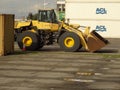 Backhoe loader parked on port waiting to be loaded to a cargo ship