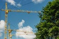 Construction site. Big industrial tower cranes with unfinished high raised buildings and blue sky in background. Scaffold. Modern