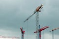 Construction site. Big industrial tower cranes with unfinished high raised buildings and blue sky in background. Scaffold. Modern