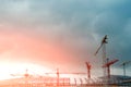 Construction site. Big industrial tower cranes with unfinished high raised buildings and blue sky in background. Scaffold. Modern