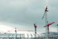 Construction site. Big industrial tower cranes with unfinished high raised buildings and blue sky in background. Scaffold. Modern