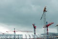 Construction site. Big industrial tower cranes with unfinished high raised buildings and blue sky in background. Scaffold. Modern