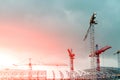 Construction site. Big industrial tower cranes with unfinished high raised buildings and blue sky in background. Scaffold. Modern