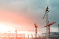 Construction site. Big industrial tower cranes with unfinished high raised buildings and blue sky in background. Scaffold. Modern