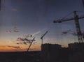 Construction site, building and crane silhouette in amazing sunset, view of city and sky. Blue and yellow sky with clouds, Royalty Free Stock Photo