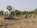 A construction site with a cement mixer truck with workers working outdoor to build a concrete fence