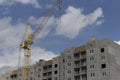 Construction site. Construction site with a crane. A concrete gray building under construction against a blue sky and clouds